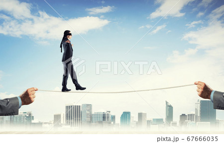 Business concept of risk support and assistance with man balancing on rope Business concept of risk support and assistance with man balancing on rope 67666035