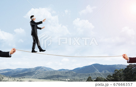 Business concept of risk support and assistance with man balancing on rope 67666357