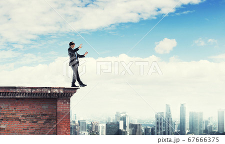 Danger and risk concept with businessman making step from edge 67666375