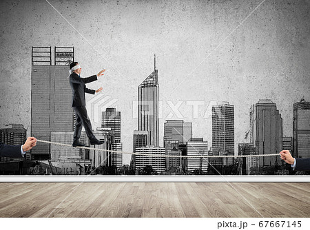 Business concept of risk support and assistance with man balancing on rope 67667145