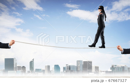 Business concept of risk support and assistance with man balancing on rope Business concept of risk support and assistance with man balancing on rope 67667327