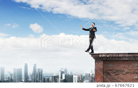 Danger and risk concept with businessman making step from edge Danger and risk concept with businessman making step from edge 67667621