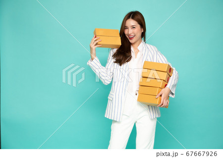 Happy Asian woman smiling and holding package parcel box isolated on light green background 67667926