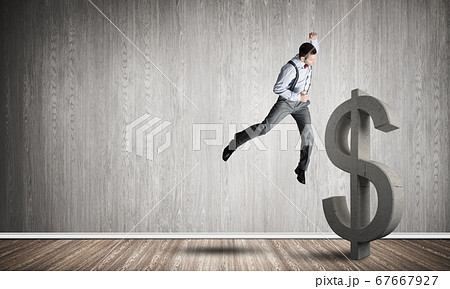 Determined banker man in empty concrete room breaking dollar figure 67667927