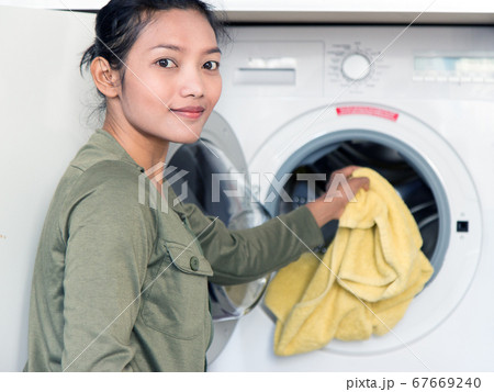 Woman holds dirty clothes and opens washing Woman holds dirty clothes and opens washing 67669240
