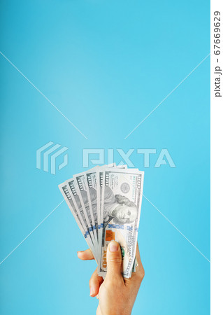 Wad of banknotes in hand on a blue background. The Wad of banknotes in hand on a blue background. The 67669629