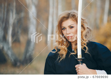 European woman with a katana in a kimono. the girl trains martial arts. a woman in the autumn forest. a warrior with a cold weapon in his hands European woman with a katana in a kimono. the girl trains martial arts. a woman in the autumn forest. a warrior with a cold weapon in his hands 67669690