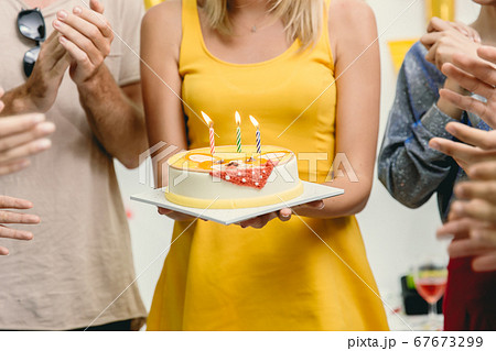Closeup woman with birthday cake in the party around with friends clap her birthday celebration 67673299