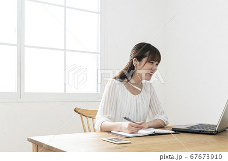 テレワーク　白いイヤフォンをつけてウェブ会議をする若い女性 67673910