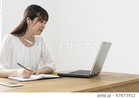 テレワーク　白いイヤフォンをつけてウェブ会議をする若い女性 67673912