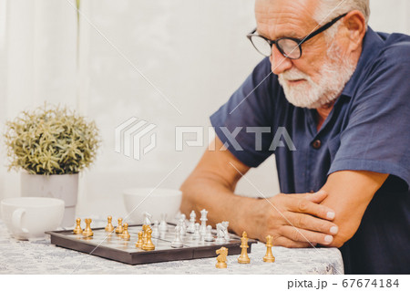 Smart Elder playing Chess board game at home for training brain memory and thinking happy smiling  67674184