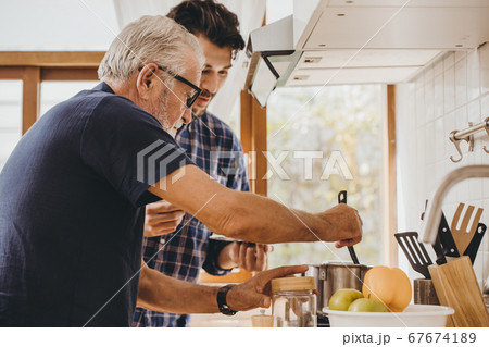 Elder cooking in the kitchen with his son, Happy family man moment good mentor old man Elder cooking in the kitchen with his son, Happy family man moment good mentor old man 67674189