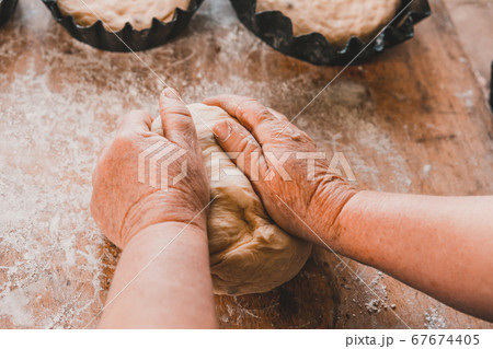 Woman kneads and shapes fresh bread into molds. 67674405