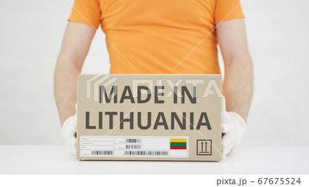 Carton with MADE IN LITHUANIA text being placed on the table 67675524