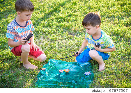Two boys playing with a spinning top kid toy. Two boys playing with a spinning top kid toy. 67677507