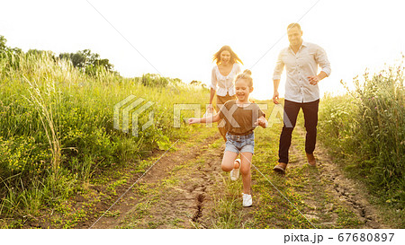 Happy parents and kid running together outdoor in summer 67680897