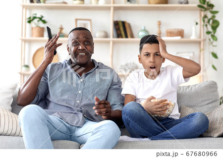 African Grandpa And Grandson Watching Sports On Tv, Emotionally Reacting To Score 67680966