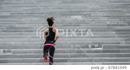 City run. Slim muscular girl in bright athletic uniform runs up the stairs 67681099
