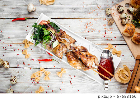 Quail barbecue skewers with salad and red sauce Quail barbecue skewers with salad and red sauce 67683166