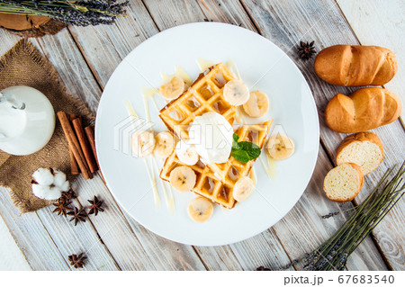 Belgian waffles poured with ice cream banana syrup 67683540