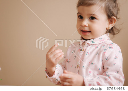 Little girl first time taste bithday cake. Cute little girl in beautiful dress tasting cake with strawberries Little girl first time taste bithday cake. Cute little girl in beautiful dress tasting cake with strawberries 67684468