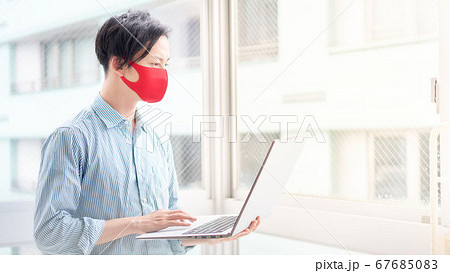 PCを使う赤いマスク着用の男性 PCを使う赤いマスク着用の男性 67685083