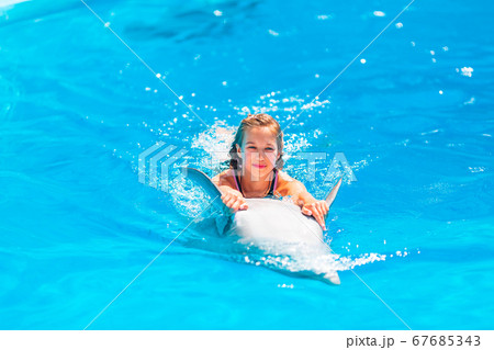 Happy little girl swimming with dolphins in 67685343