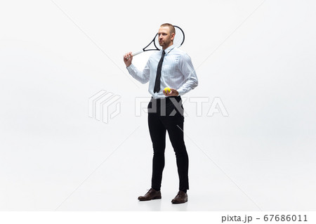 Time for movement. Man in office clothes plays tennis isolated on white studio background. Time for movement. Man in office clothes plays tennis isolated on white studio background. 67686011