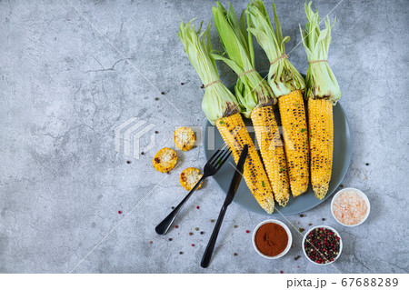 Grilled or roasted sweet corn cobs with spices. Mexican street corn on light gray stone background, top view Grilled or roasted sweet corn cobs with spices. Mexican street corn on light gray stone background, top view 67688289
