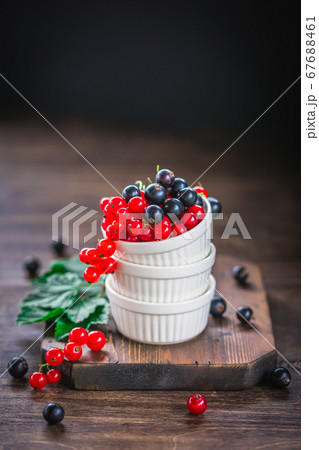 Red and black currant berries in ceramic bowl on a wooden background 67688461