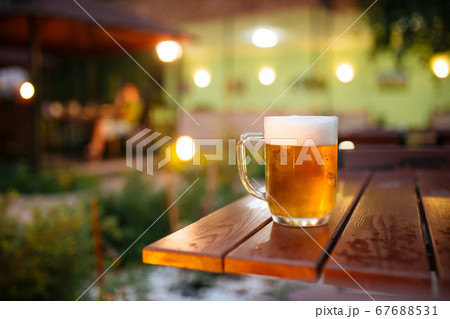 Beer with foam outside blurry lights background 67688531