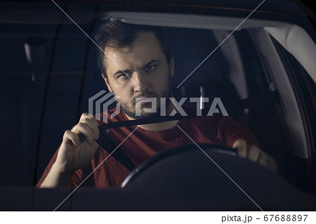 Young bearded man fastens his seat belt in a car. Safe driving 67688897