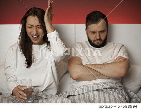 couple arguing in bed. girl screams while her boyfriend sits with offended look 67688994