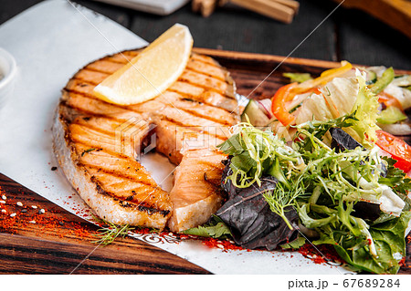 Grilled salmon steak with greens salad and lemon 67689284