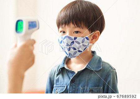 非接触体温計で検温をする男の子 67689592