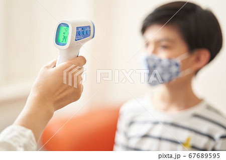非接触体温計で検温をする男の子 67689595