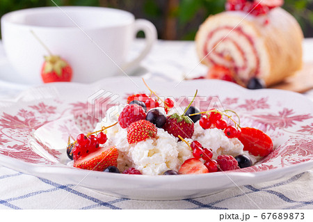 dessert with fresh berries on a red vintage plate. Farm cottage cheese 67689873