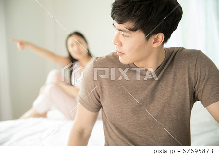 ベッドルームでケンカしている若い夫婦カップル 67695873