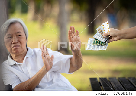 Hand of caregiver giving medicine pills and capsules to the elderly,asian senior woman refusing to take medication,afraid,bad side effects of drugs,old patient anti to medical,fear of wrong treatment Hand of caregiver giving medicine pills and capsules to the elderly,asian senior woman refusing to take medication,afraid,bad side effects of drugs,old patient anti to medical,fear of wrong treatment 67699145