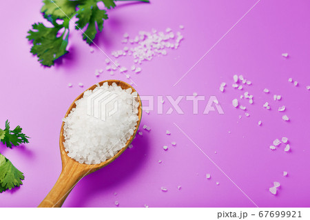 Large white sea salt in a wooden spoon on a pink Large white sea salt in a wooden spoon on a pink 67699921