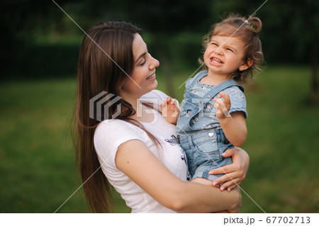 Portrait of beautiful mom with adorable little girl. Happy family outdoors. Mom and daughter laughing 67702713