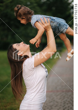 Side view of mom hold little girl on hands and have fun 67702738