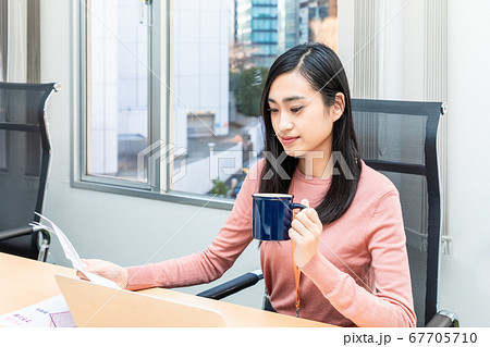 コーヒーを飲みながら仕事をする女性社員 67705710