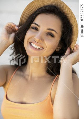 Beautiful brunette girl in a straw hat smiling nicely 67707175