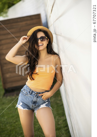 Pretty brunette girl in jeans shorts looking pleased Pretty brunette girl in jeans shorts looking pleased 67707321