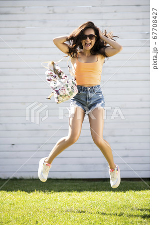 Pretty brunette girl in shorts jumping and smiling Pretty brunette girl in shorts jumping and smiling 67708427