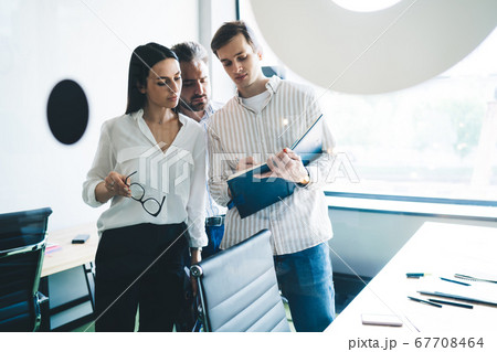 Man writing in notebook while standing in office Man writing in notebook while standing in office 67708464