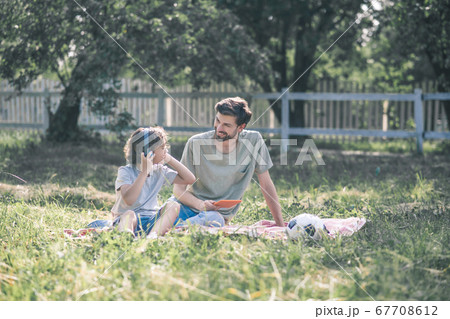 A boy in earphones sitting near his dad and listening to music A boy in earphones sitting near his dad and listening to music 67708612