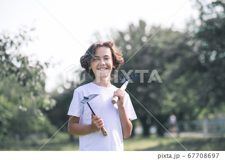 Dark-haired boy holding gardening equipment and smiling Dark-haired boy holding gardening equipment and smiling 67708697