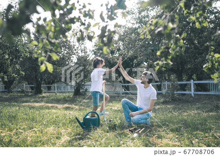 Dark-haired boy and his dad doing high five and feeling wonderful 67708706